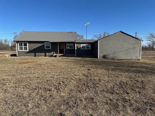 rear view of house with a lawn and metal roof