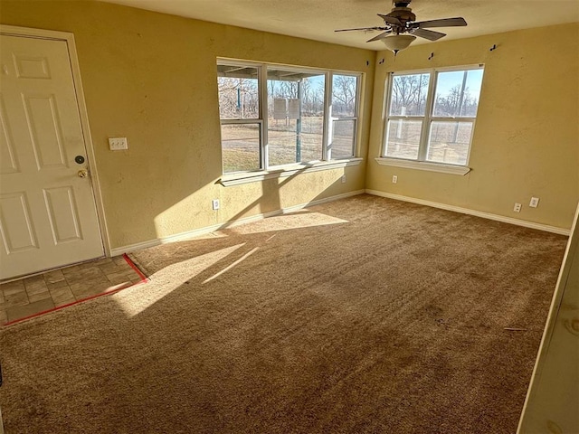 carpeted spare room featuring a ceiling fan, baseboards, and a textured wall