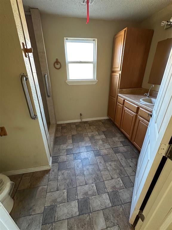 full bath with visible vents, a textured ceiling, a shower stall, baseboards, and vanity