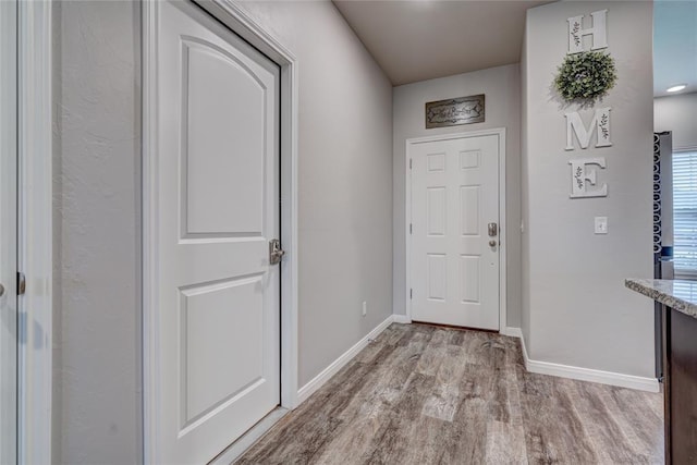 doorway with light wood-style flooring and baseboards