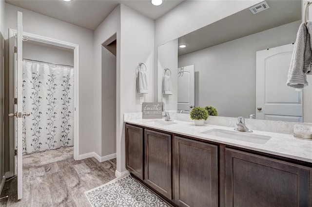 full bathroom with double vanity, wood finished floors, a sink, and visible vents