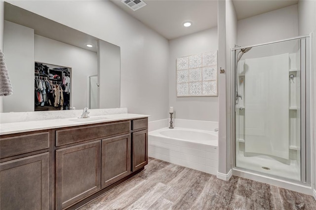 full bathroom featuring visible vents, a spacious closet, a stall shower, wood finished floors, and a bath