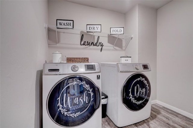 clothes washing area with laundry area, light wood-style flooring, baseboards, and separate washer and dryer