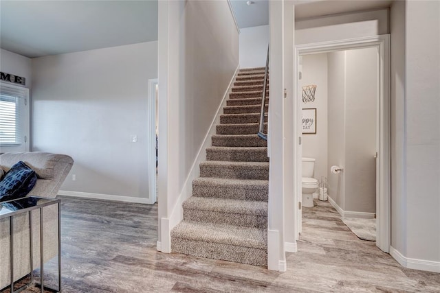 staircase featuring wood finished floors and baseboards