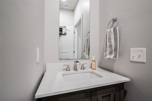 bathroom with visible vents, a textured wall, and vanity