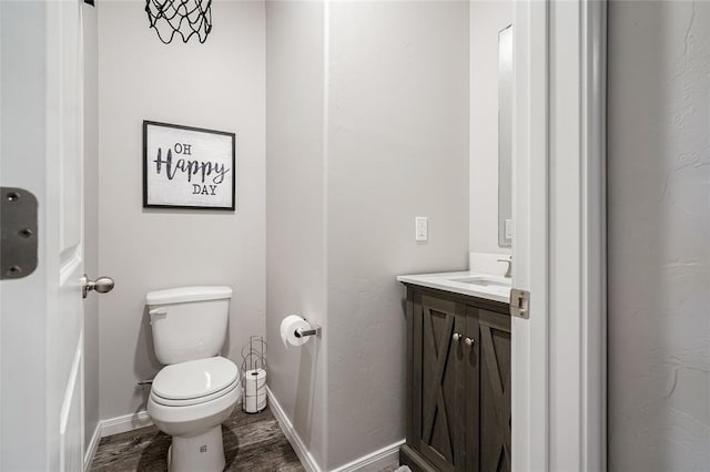 bathroom with baseboards, vanity, and toilet