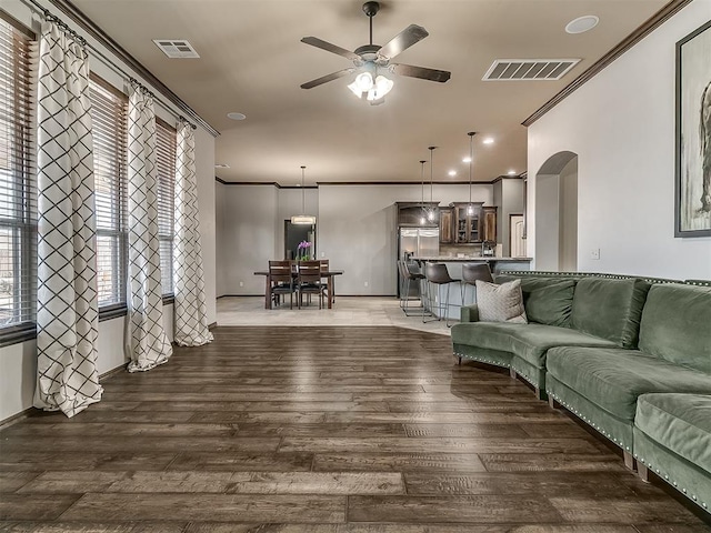 living area featuring visible vents, ornamental molding, ceiling fan, and wood finished floors