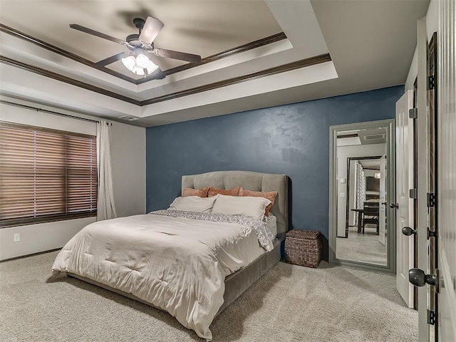 carpeted bedroom featuring a tray ceiling and a ceiling fan