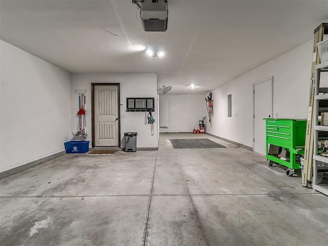 garage featuring electric panel, a garage door opener, and baseboards