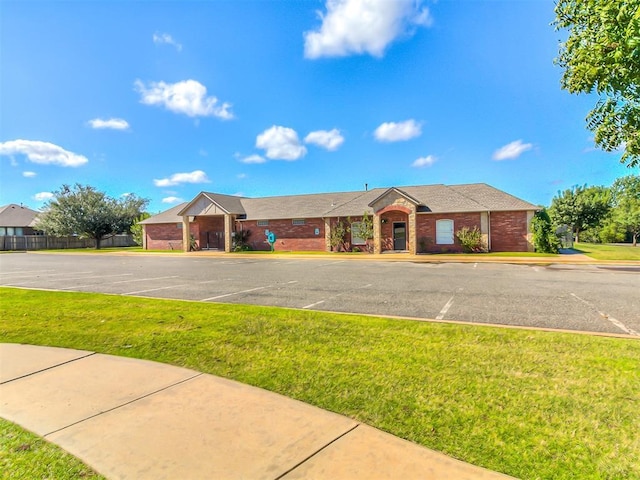 ranch-style house featuring a front lawn, uncovered parking, and brick siding