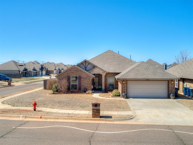 french country style house featuring driveway, brick siding, roof with shingles, and an attached garage