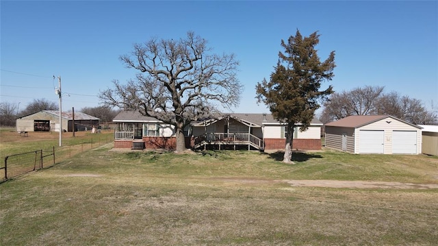 view of front of property featuring a garage, an outdoor structure, fence, a wooden deck, and a front lawn