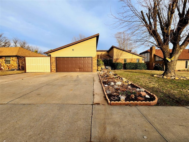 view of side of property featuring a garage, brick siding, and driveway