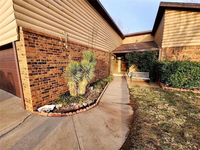 view of home's exterior with a garage, log veneer siding, and brick siding