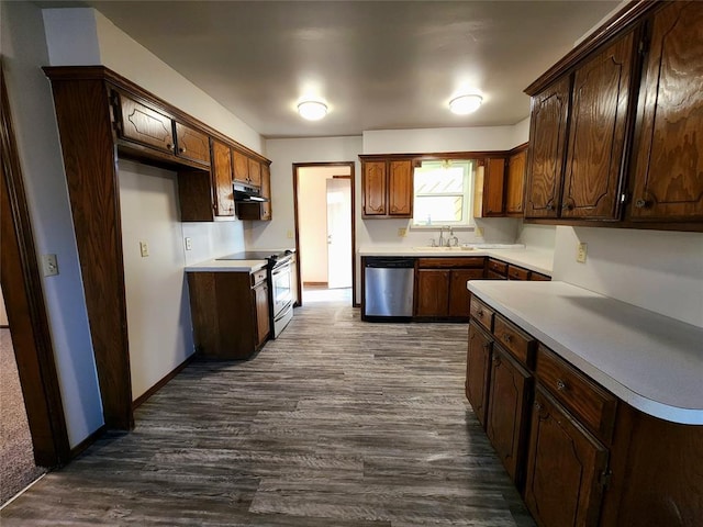 kitchen featuring dark wood-style flooring, light countertops, appliances with stainless steel finishes, a sink, and under cabinet range hood