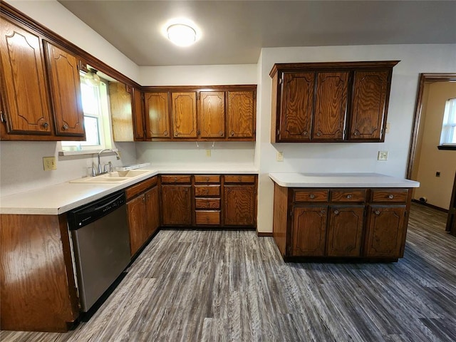 kitchen with dark wood-type flooring, light countertops, a sink, and stainless steel dishwasher