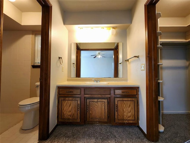 bathroom featuring toilet, baseboards, vanity, and a ceiling fan