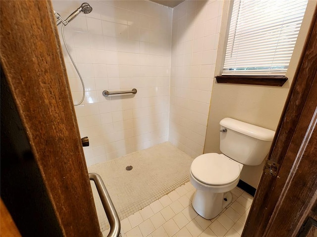 full bathroom featuring toilet, baseboards, a tile shower, and tile patterned floors