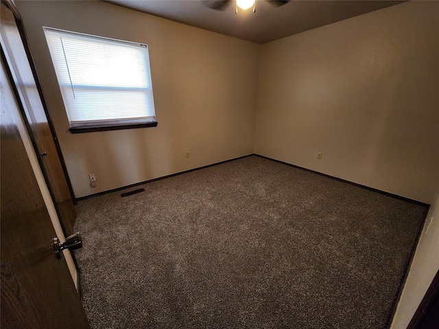 empty room with carpet floors, baseboards, visible vents, and ceiling fan