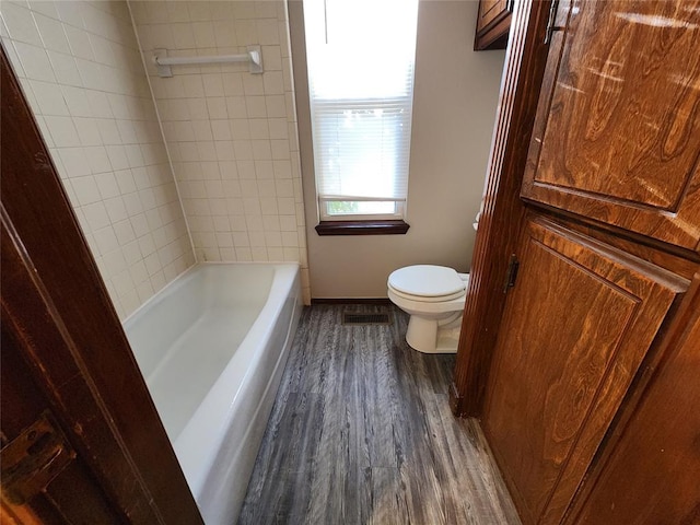 bathroom with baseboards, a shower, toilet, wood finished floors, and a bathtub