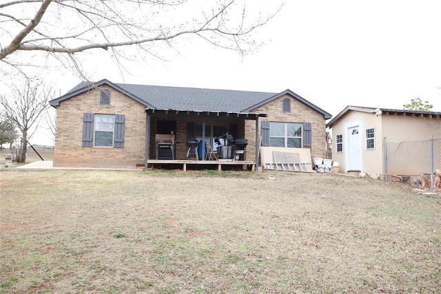 ranch-style home featuring a shingled roof, a front yard, and brick siding