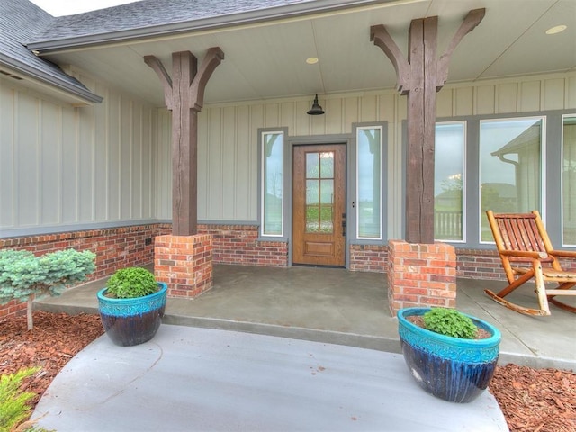 entrance to property featuring brick siding, board and batten siding, and roof with shingles