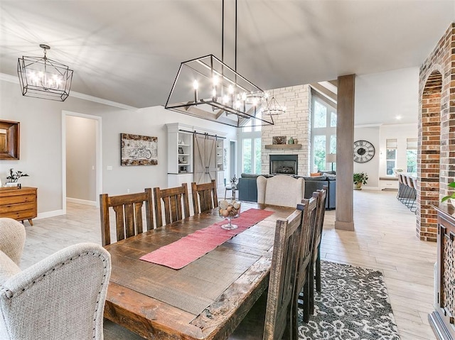 dining area featuring crown molding, light wood-type flooring, a wealth of natural light, and a large fireplace