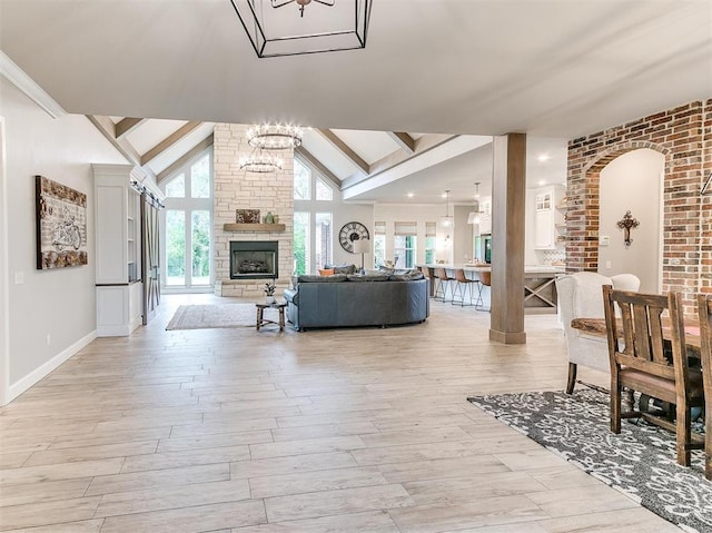 living area featuring high vaulted ceiling, an inviting chandelier, light wood-style flooring, and a fireplace