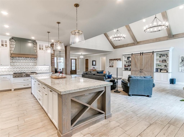 kitchen featuring lofted ceiling with beams, custom range hood, open floor plan, a barn door, and tasteful backsplash