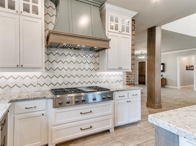 kitchen featuring light stone countertops, decorative backsplash, custom range hood, stainless steel gas stovetop, and crown molding