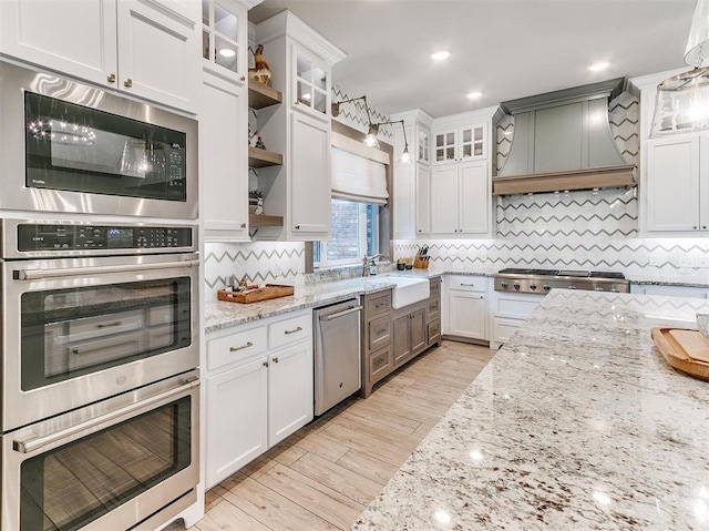 kitchen featuring a sink, white cabinets, stainless steel appliances, and premium range hood