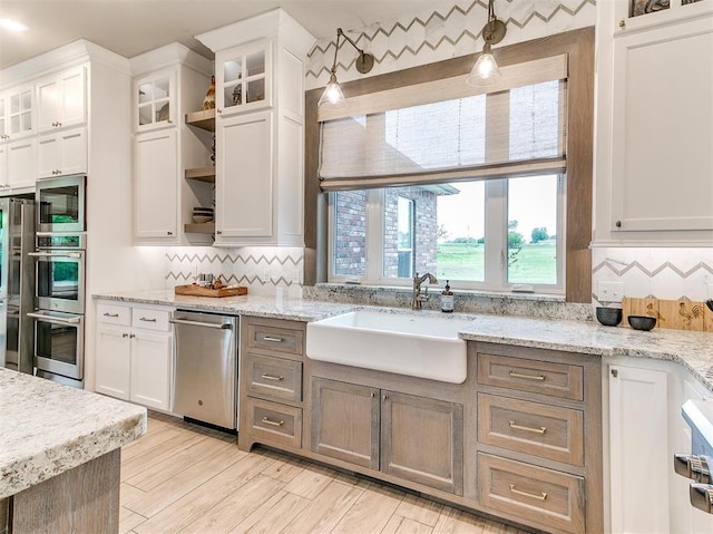 kitchen with a sink, open shelves, appliances with stainless steel finishes, white cabinets, and decorative backsplash