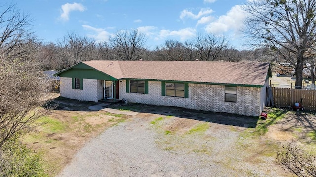 ranch-style house with brick siding, fence, and driveway