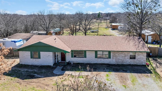 ranch-style home featuring brick siding, roof with shingles, and fence