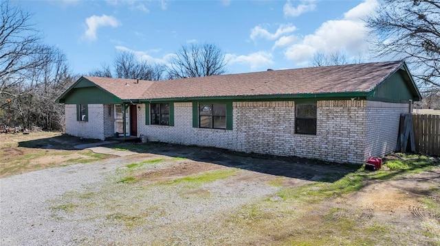 ranch-style home with driveway, brick siding, and fence