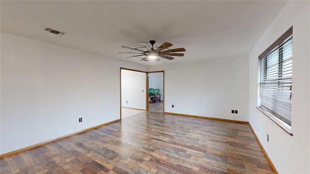 empty room featuring a ceiling fan, wood finished floors, visible vents, and baseboards