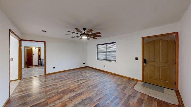 spare room featuring a ceiling fan, visible vents, baseboards, and wood finished floors