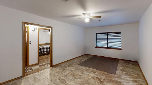 spare room featuring baseboards, visible vents, and a ceiling fan