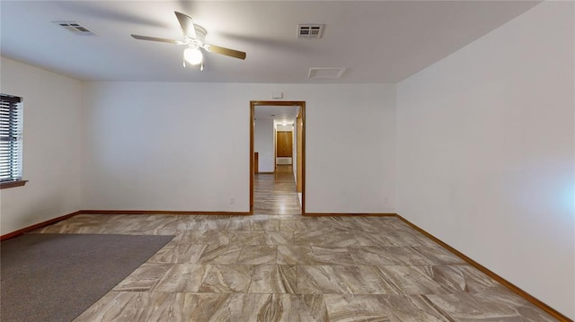 spare room featuring ceiling fan, visible vents, and baseboards