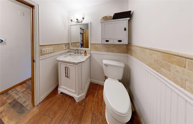 bathroom featuring a wainscoted wall, vanity, wood finished floors, and toilet