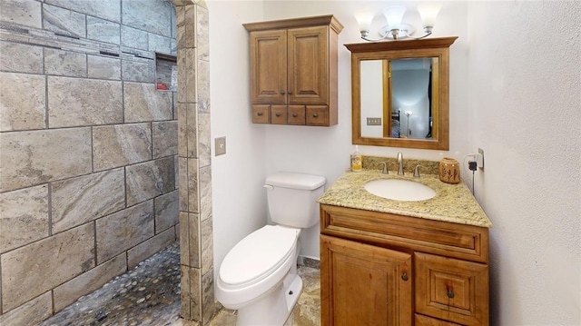 full bathroom with tiled shower, a notable chandelier, vanity, and toilet