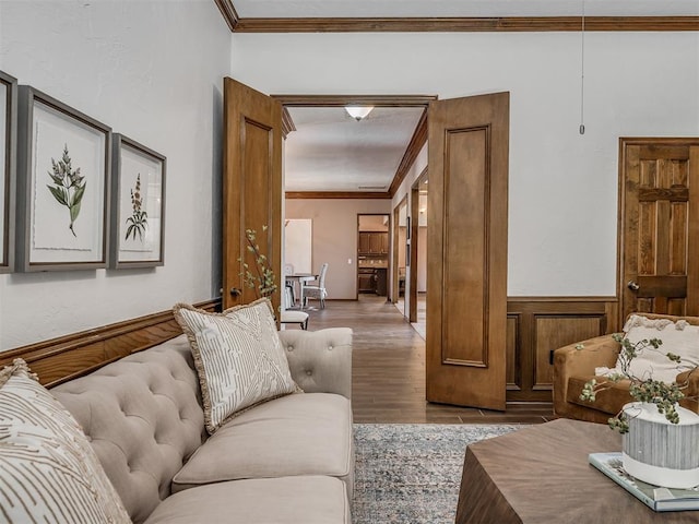 living area with a wainscoted wall, ornamental molding, and wood finished floors