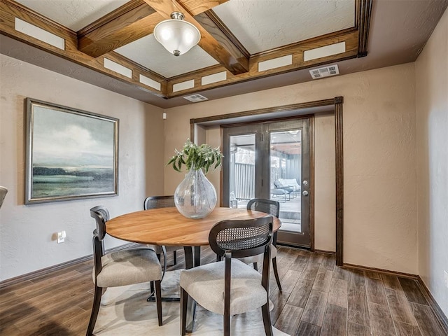 dining area with visible vents, beamed ceiling, wood finished floors, and a textured wall