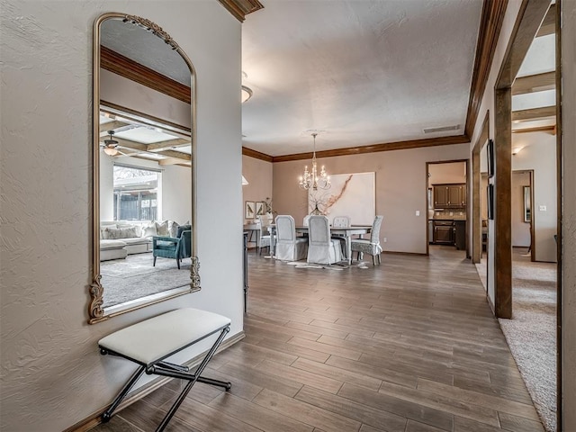 dining space featuring ornamental molding, visible vents, a textured wall, and wood finished floors