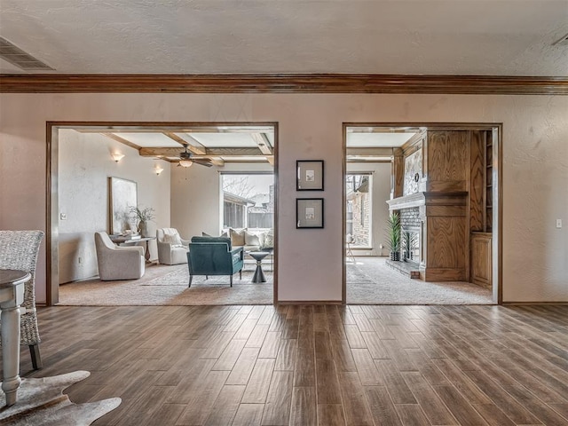 foyer with a brick fireplace, visible vents, a textured ceiling, and wood finished floors