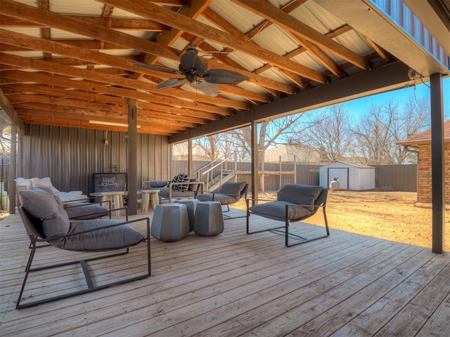 wooden terrace featuring a ceiling fan, a fenced backyard, an outdoor structure, a shed, and an outdoor living space