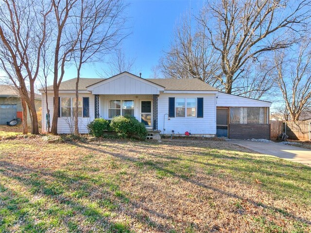 420 W Lincoln St, Purcell, OK 73080 - view of front of property featuring driveway, a sunroom, roof with shingles, fence, and a front lawn