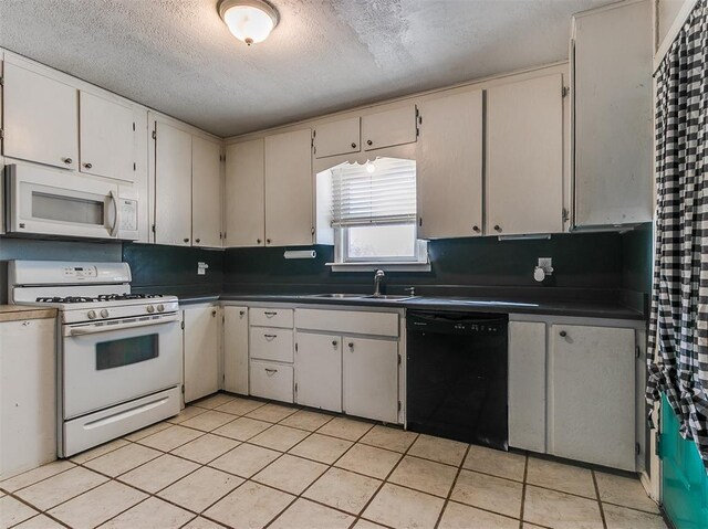 420 W Lincoln St, Purcell, OK 73080 - kitchen with dark countertops, white appliances, a sink, and a textured ceiling