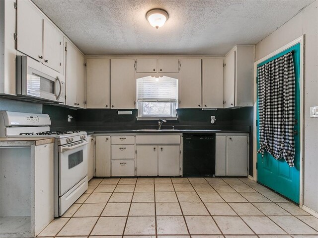 420 W Lincoln St, Purcell, OK 73080 - kitchen with a textured ceiling, light tile patterned floors, white appliances, a sink, and dark countertops