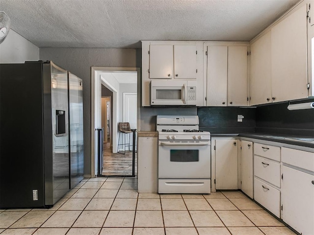 420 W Lincoln St, Purcell, OK 73080 - kitchen featuring dark countertops, white appliances, white cabinets, and light tile patterned floors